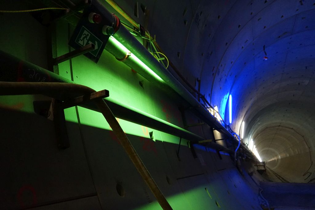 Im Vordergrund leuchtet in Grün die Kennzeichnung der Fluchtwege. Im Hintergrund leuchtet eine Entnahmestelle für Löschwasser blau.
